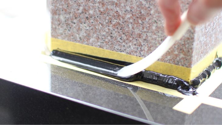 お墓の目地にコーキングを施した後、仕上げ用ヘラでコーキングをならしている画像